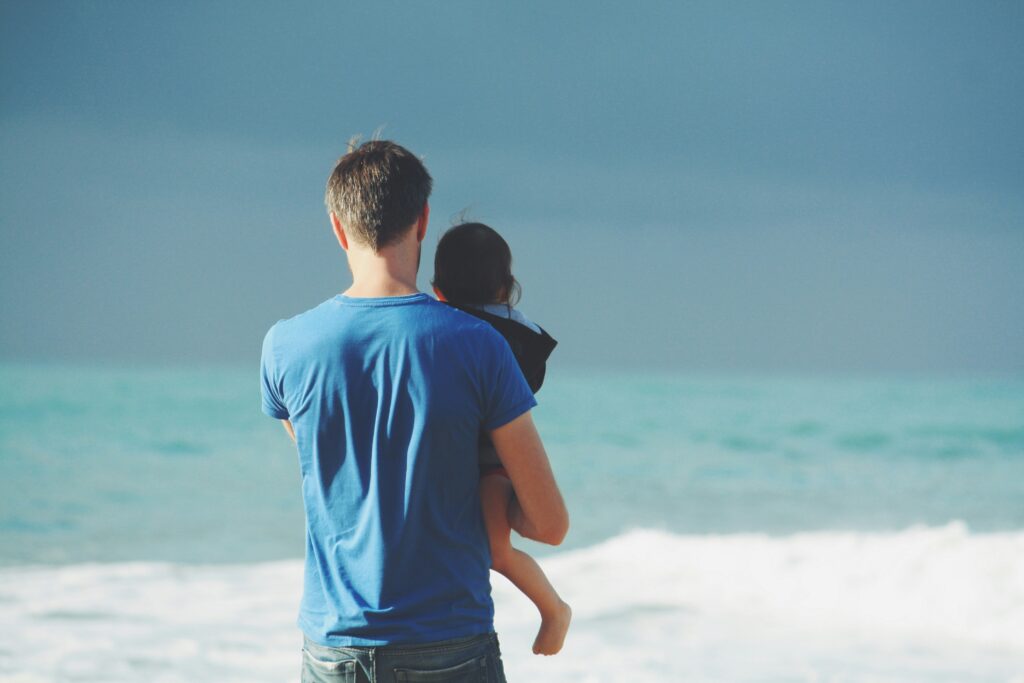 man holding child at beach